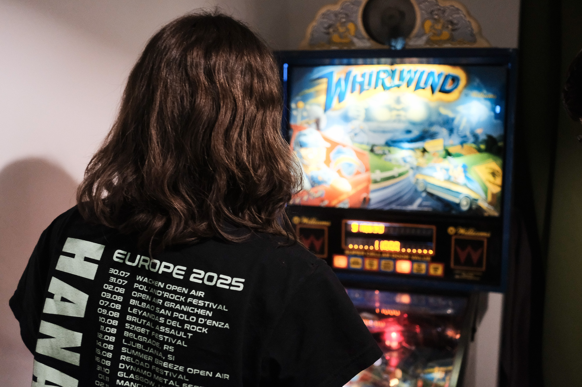 Picture from the back of a person (Kumi) playing Pinball (Williams Whirlwind).