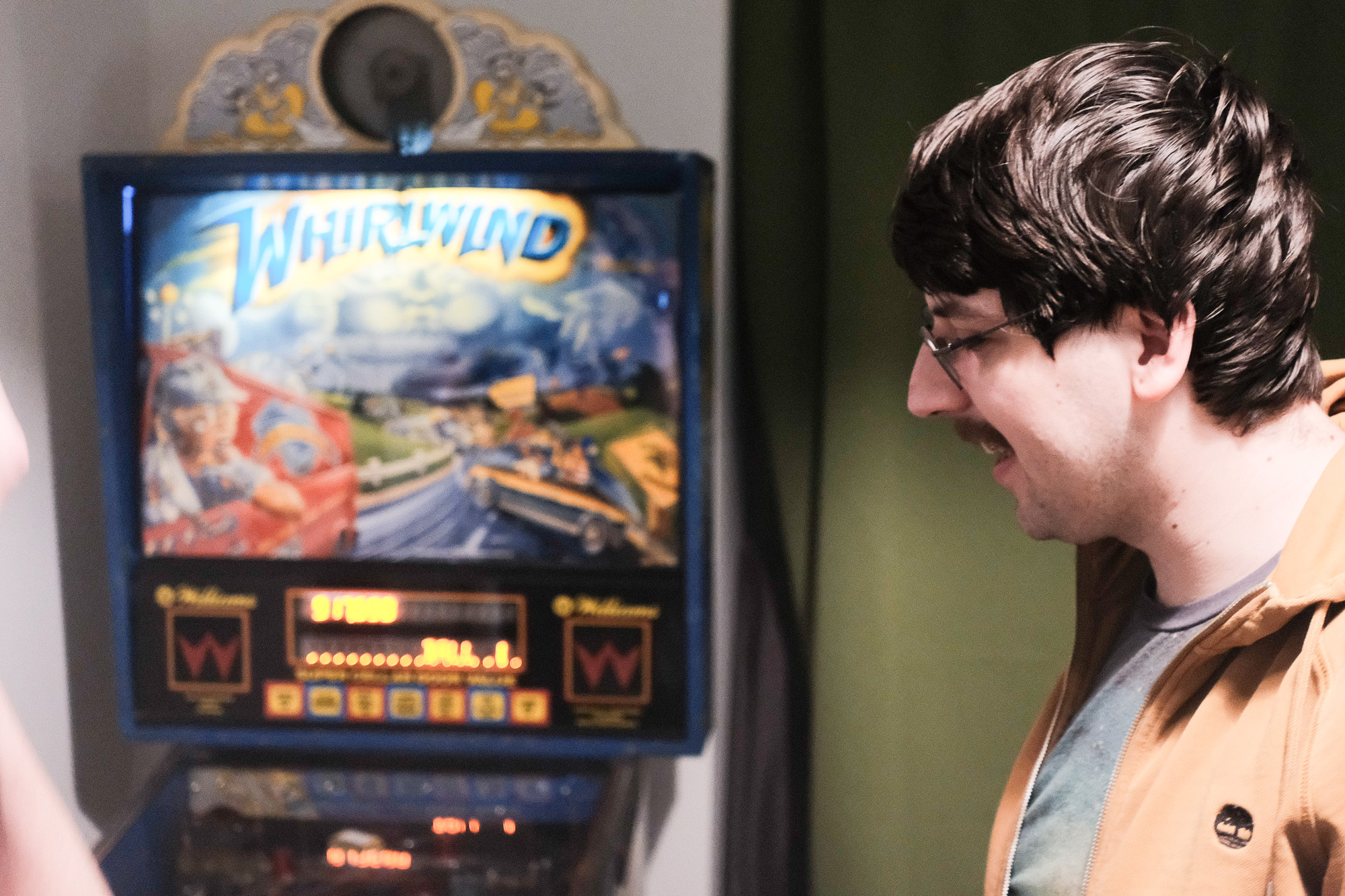 Picture from the side of a person (ogalbnafets) standing next to a pinball machine (Williams Whirlwind).